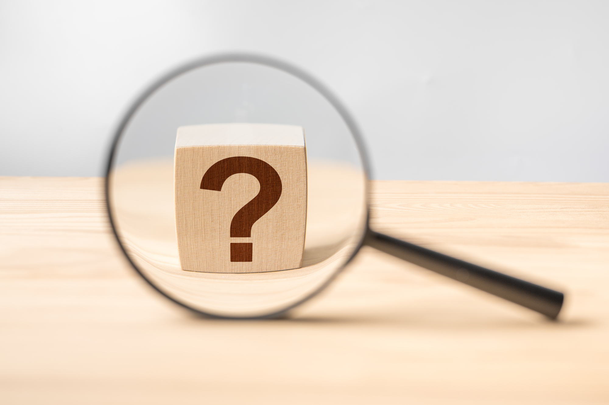 Magnifying glass with question mark in focus on wooden background. concept of search and research. search for an answer to question